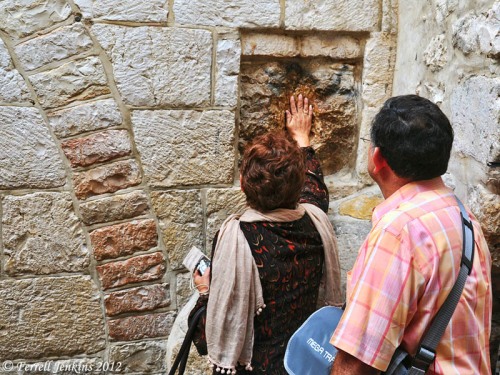 A woman places her hand on a stone at the fifth station of the cross. Photo by Ferrell Jenkins.